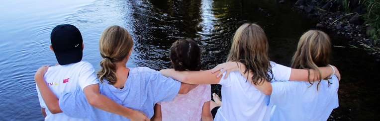 picture of kids sitting on a dock at a lake